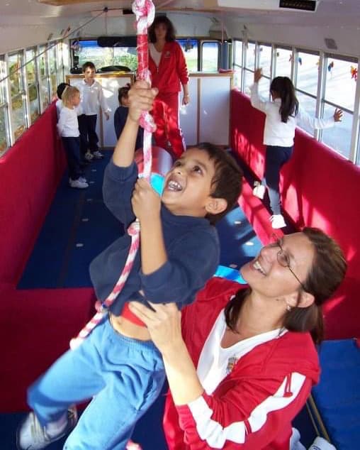Child climbing a rope in the mobile fitness bus.